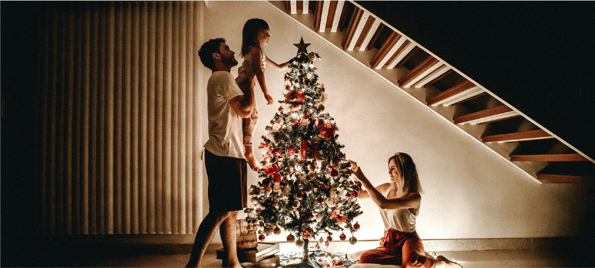 parents and their daughter decorate a christmas tree