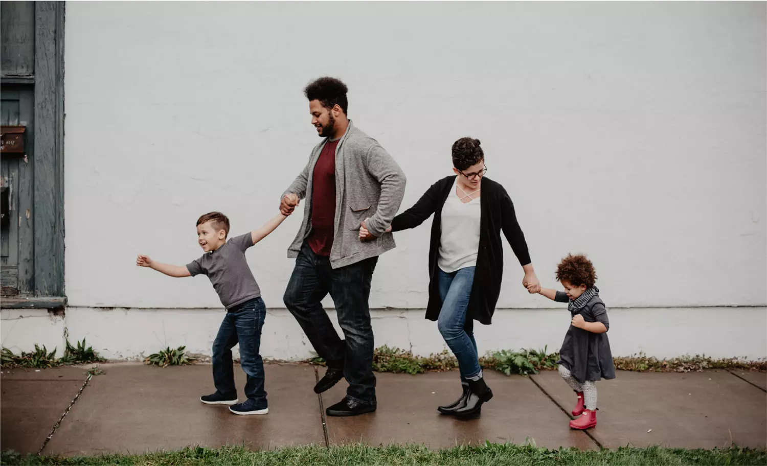 parents and their two young children walking in a line on the sidewalk