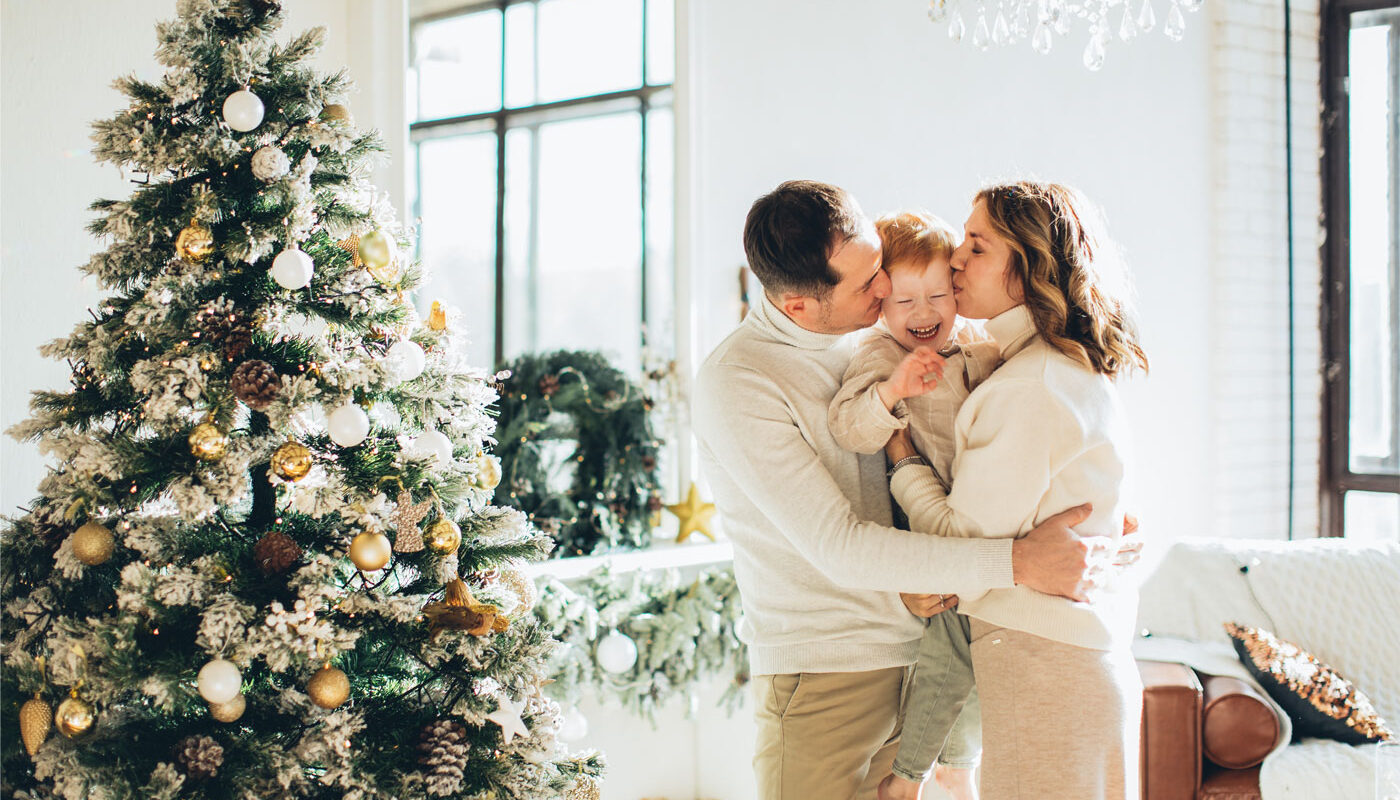 parents and their son hug by the decorated christmas tree