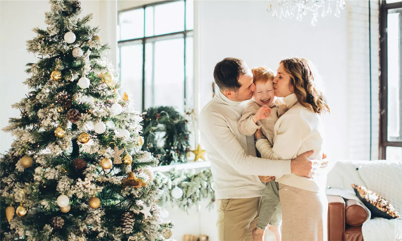parents and their son hug by the decorated christmas tree