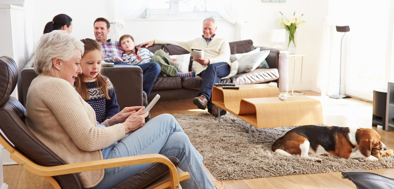 a multigenerational family sits in their living room talking and reading