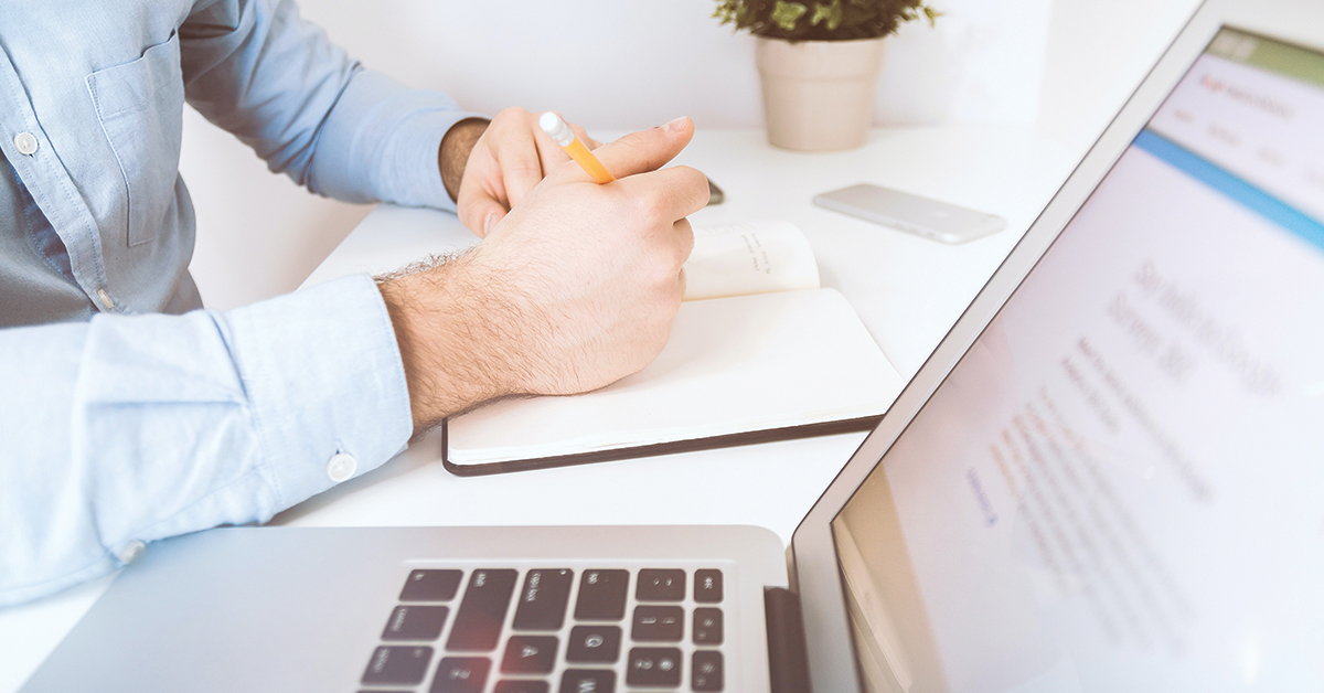 a man writing in a journal and looking at his computer on a site discussing donor advised funds