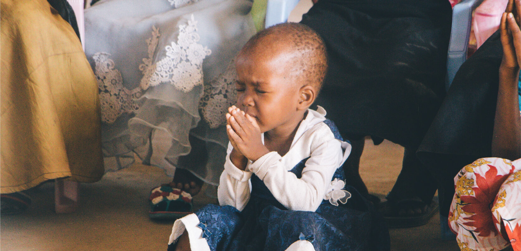 a young child sitting on the floor praying