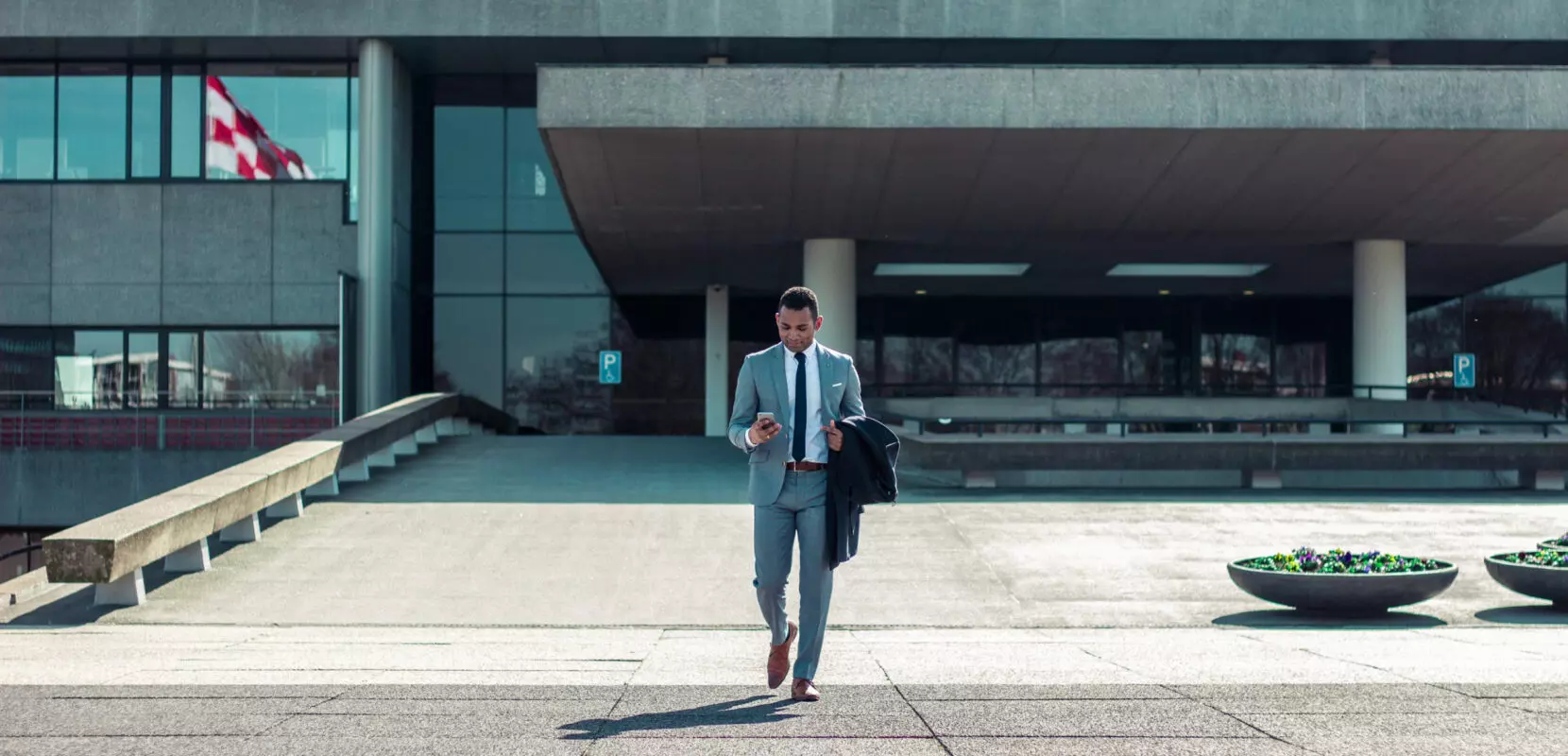 a business man walks out of a building on his phone discussing real estate