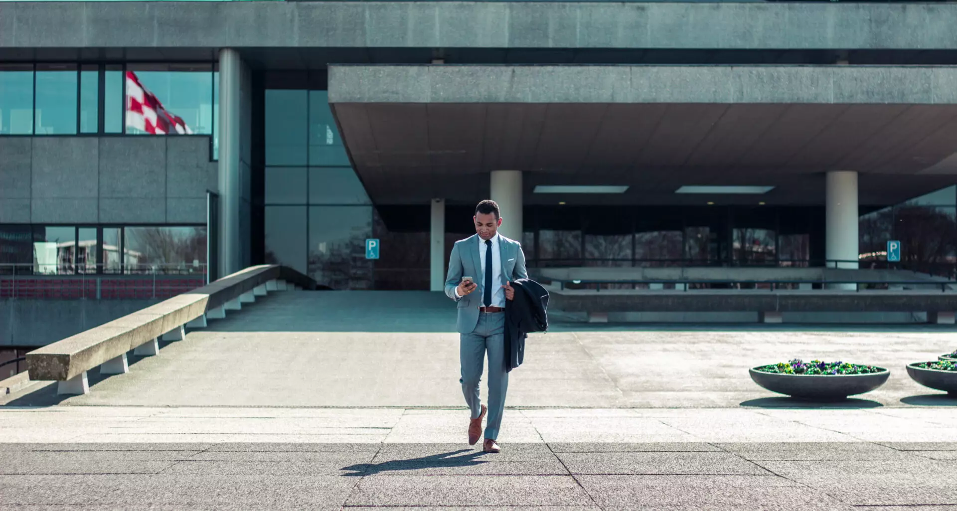 a business man walks out of a building on his phone discussing real estate