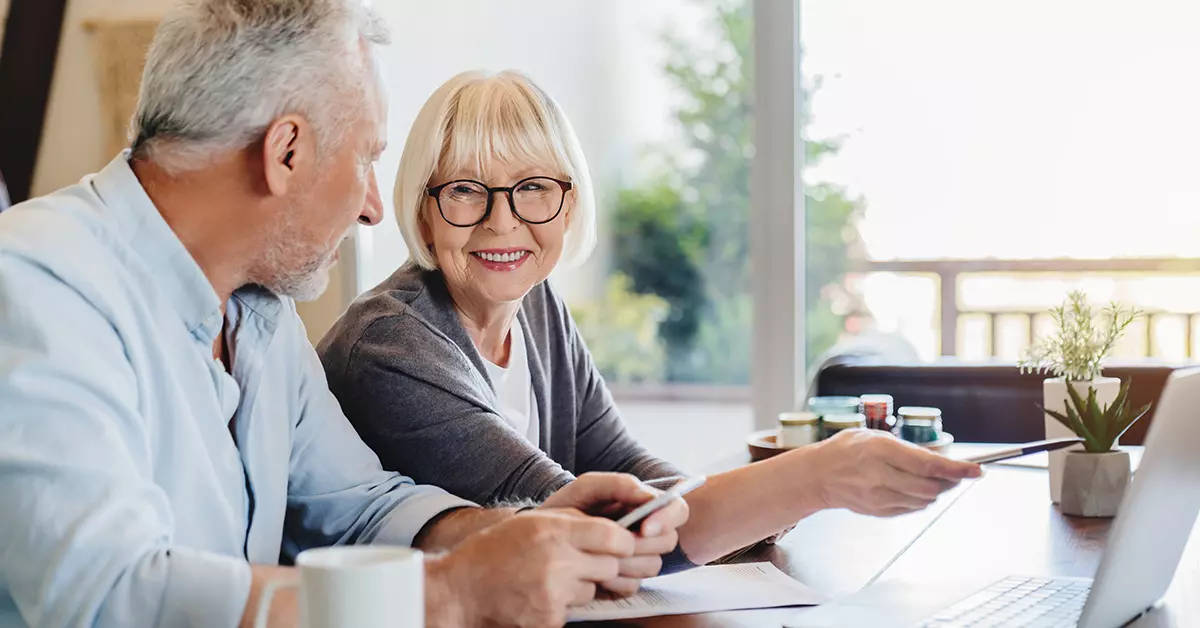 older couple discussing year end plans at the kitchen table while looking at their computer