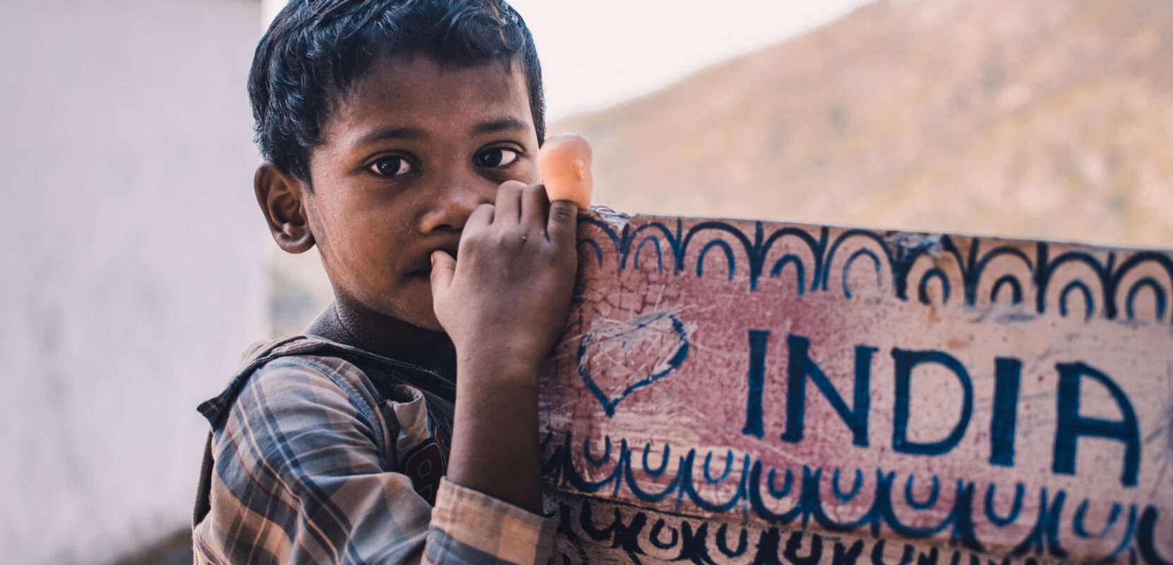 a young child sits next to a sign that says "india"