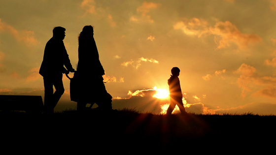 family on a walk through a meadow at sunset