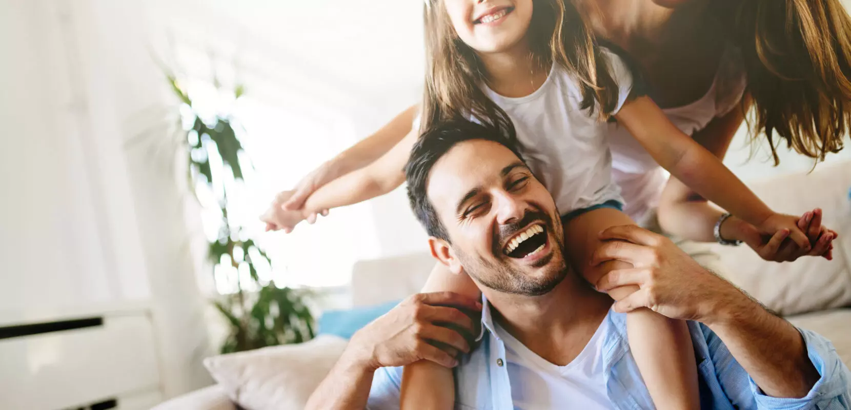 a father carries his daughter on his shoulders with the mother behind them
