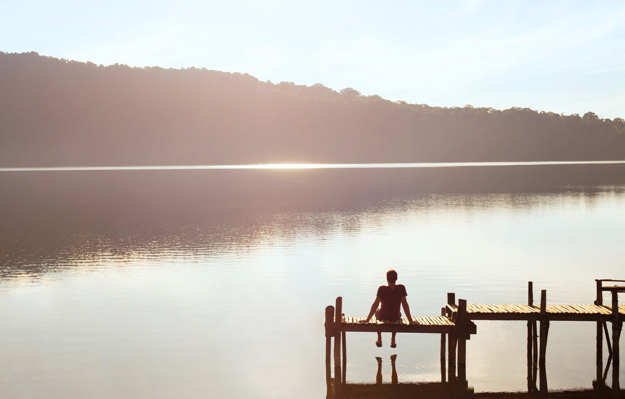 a man sitting on a dock over a lake