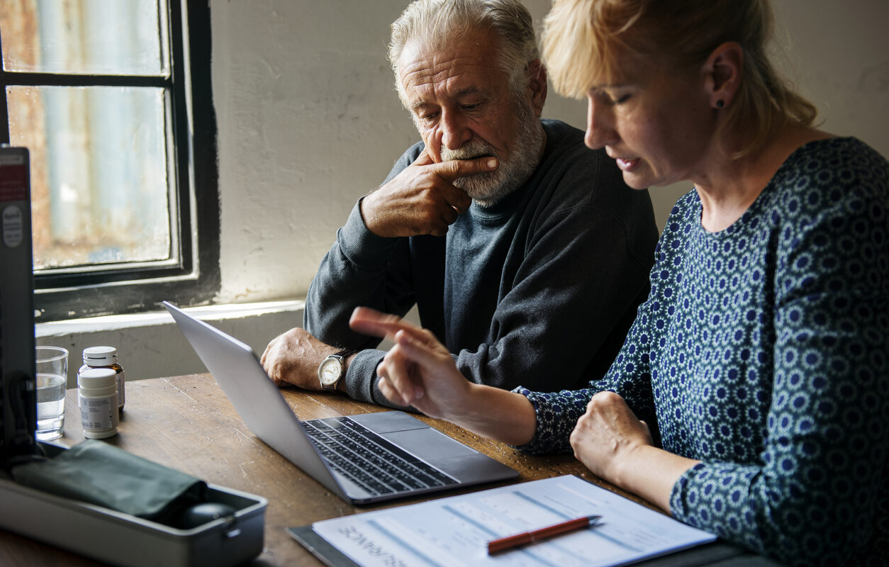 an older couple create a giving plan on their computer at the table