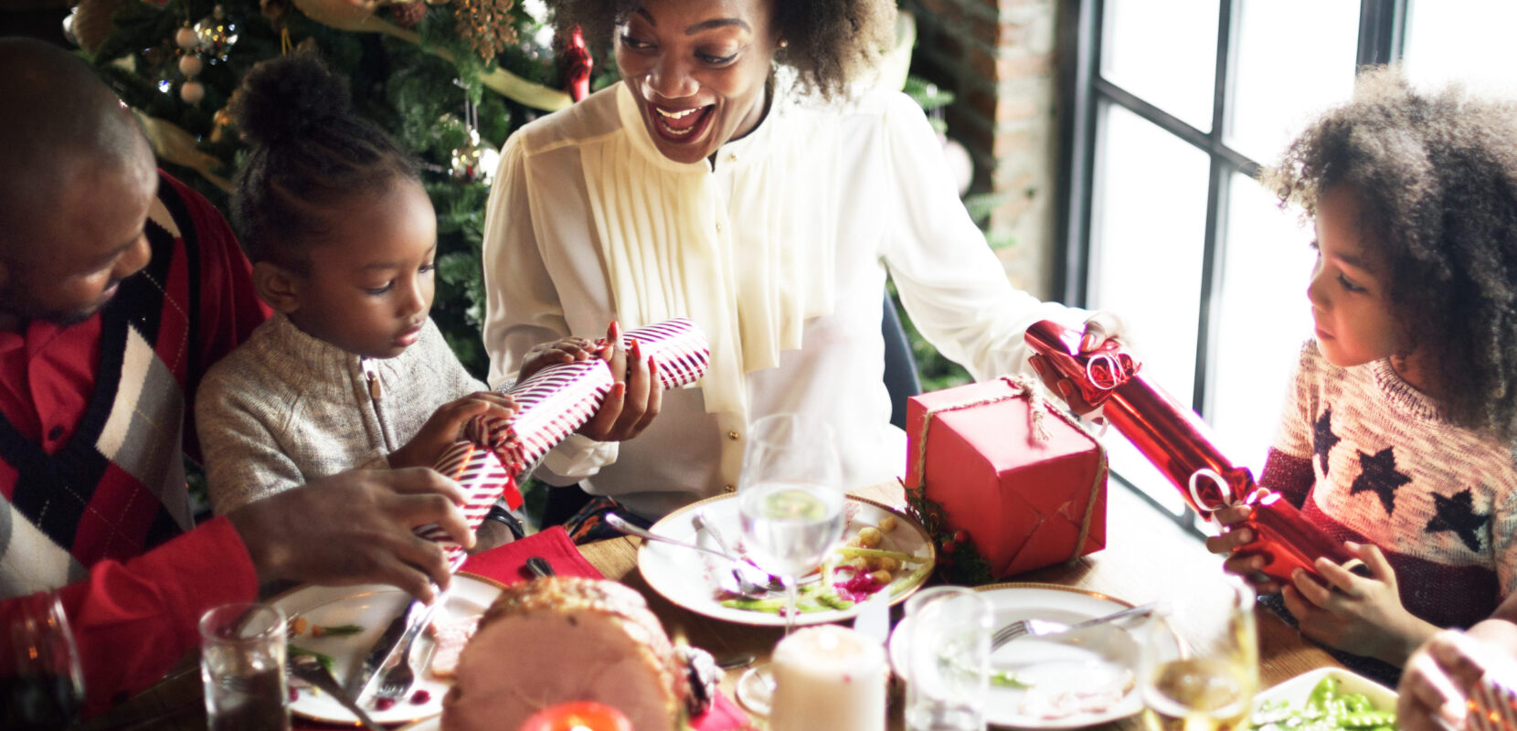 a family of four shares christmas gifts and dinner around a table