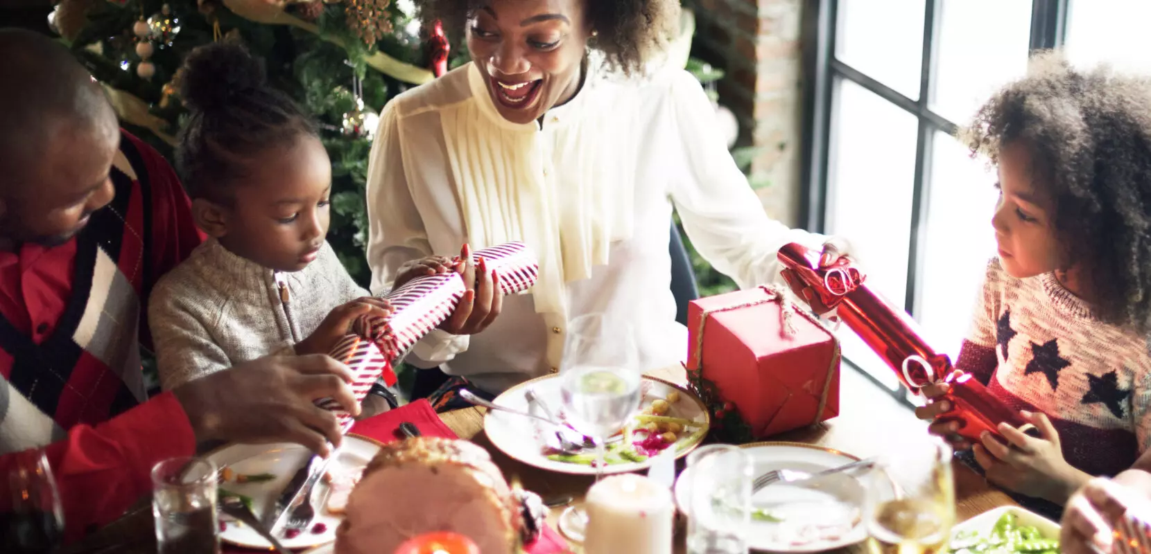 a family of four shares christmas gifts and dinner around a table