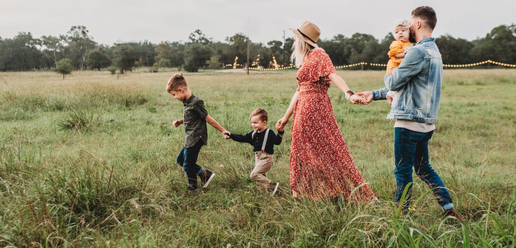 a family of five walk through a meadow holding hands