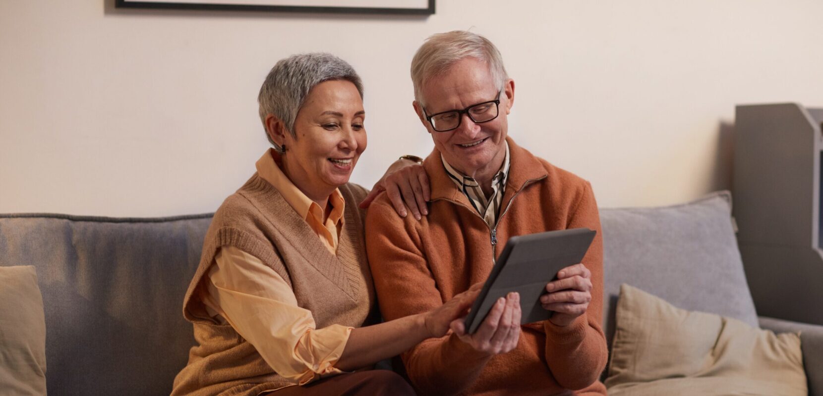 a husband and wife sit on the couch with their ipad to go over what they need to know about charitable giving and taxes for 2023