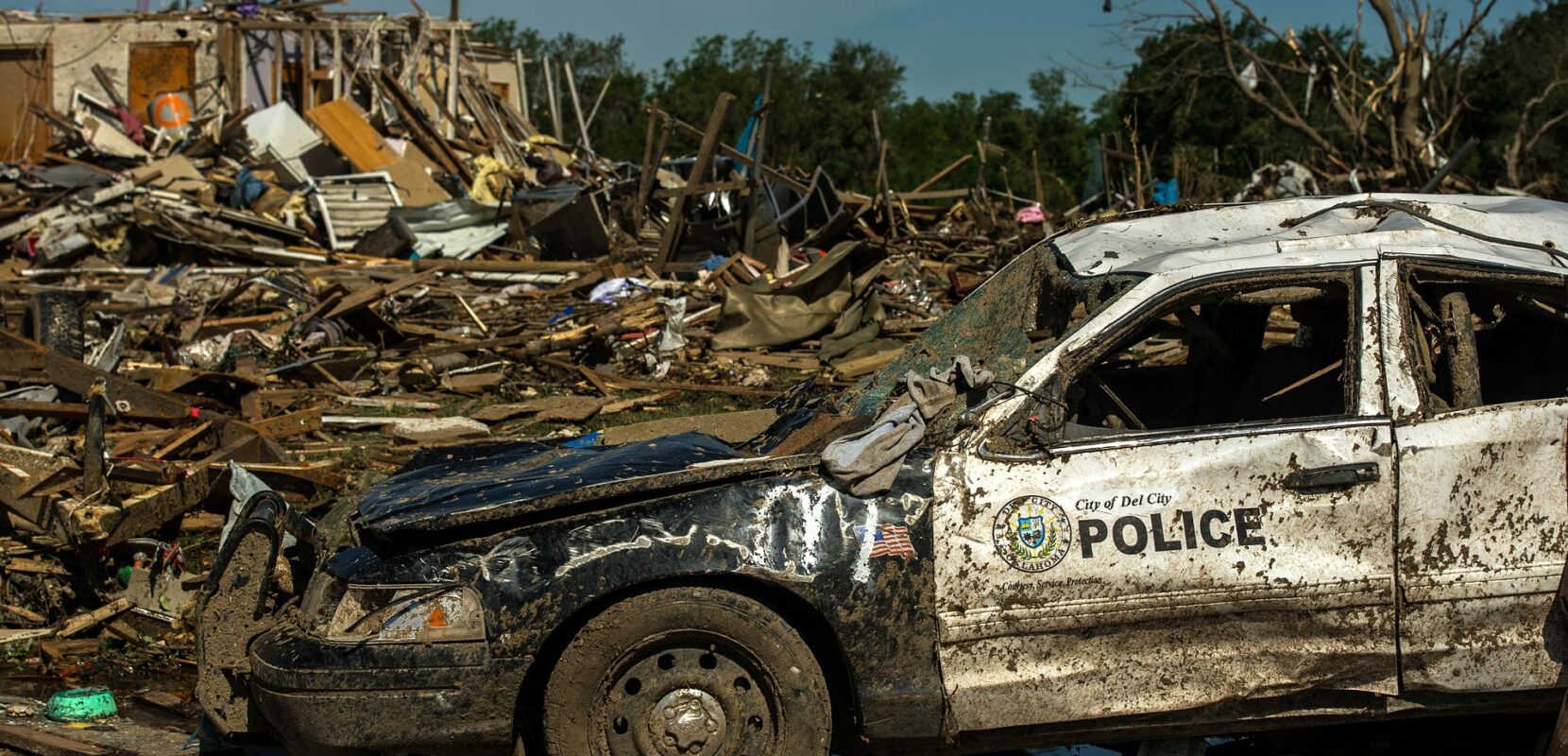 the aftermath of a tornado with a destroyed house and police car