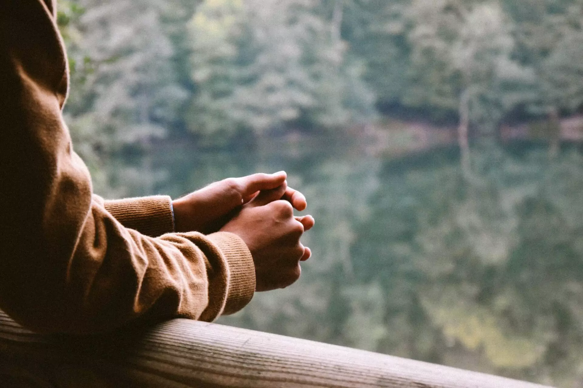 someone reflecting on a bridge overlooking a pond